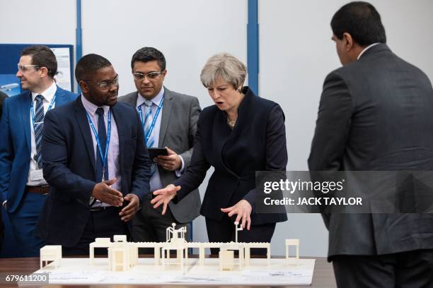 British Prime Minister Theresa May is shown a display as she tours the UTC Aerospace Systems factory in Wolverhampton, central England on May 6 as...