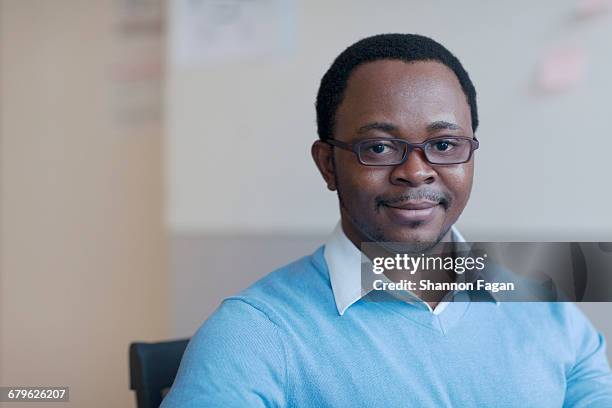 portrait of man sitting smiling in office - patience office stock pictures, royalty-free photos & images