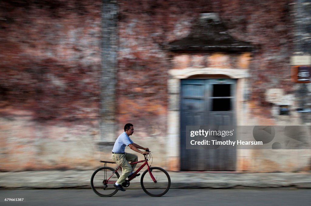 Bicyclist on street with colonial building beyond