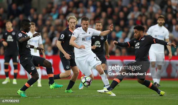 Gylfi Sigurdsson of Swansea City attempts to get past Ashley Williams of Everton and Idrissa Gueye of Everton during the Premier League match between...