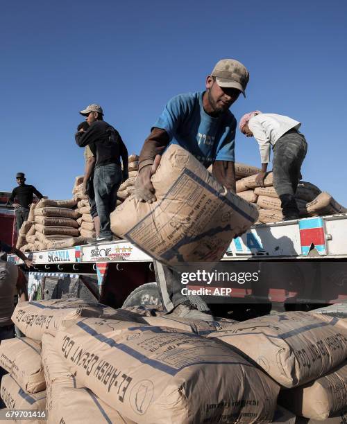 Palestinian workers unload bags of cement from a truck after it entered the southern Gaza Strip from Egypt through the Rafah border crossing, after...