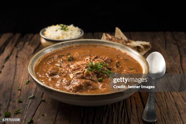 a bowl of lamb curry served with naan bread and rice. - lamb photos et images de collection