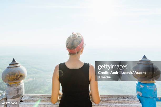 Young woman explores Buddhist temple, above plain