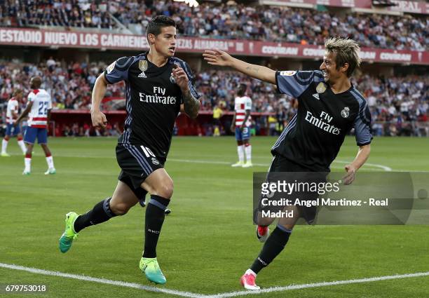 James Rodriguez of Real Madrid celebrates with Fabio Coentrao after scoring their team's second goal during the La Liga match between Granada CF and...