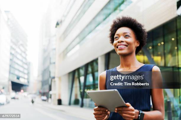 woman looking up with tablet - african american woman with tablet stock-fotos und bilder