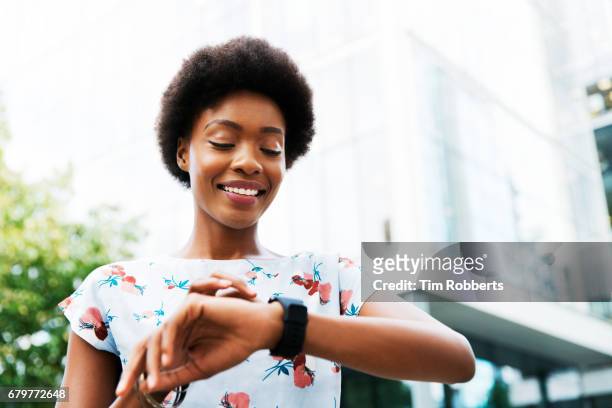 smiling woman using smart watch - afro frisur stock-fotos und bilder
