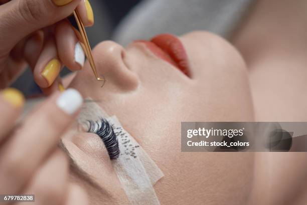 tratamiento de belleza, aplicando false eyelashes - eyelash fotografías e imágenes de stock