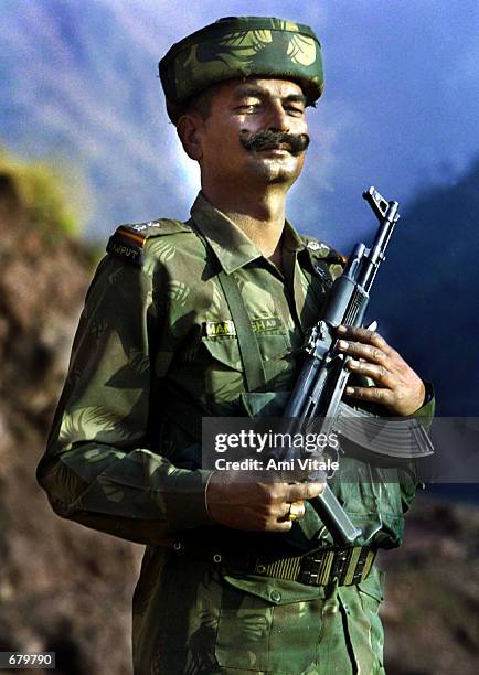 An Indian soldier watches smoke billow after a rocket was launched at armed militants hiding in a villager's house November 2, 2001at the Poonch...