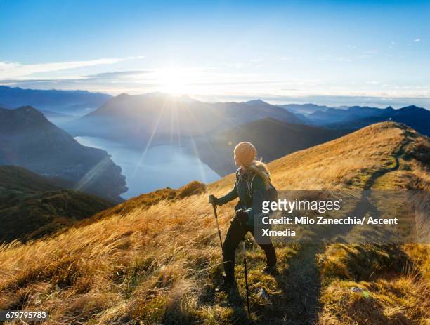 woman hikes along ridgecrest above lake, valley - zwitserland stock-fotos und bilder