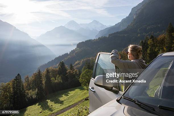 woman pauses by car door, looks out over mtns - car door stock pictures, royalty-free photos & images