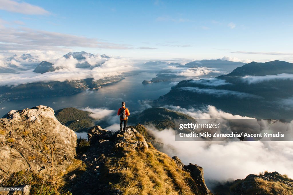 Male hiker pauses on ridgecrest above lake, valley