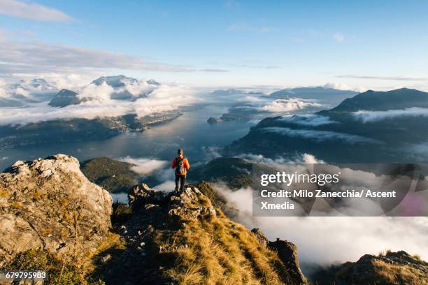 male hiker pauses on ridgecrest above lake, valley - switzerland stock-fotos und bilder