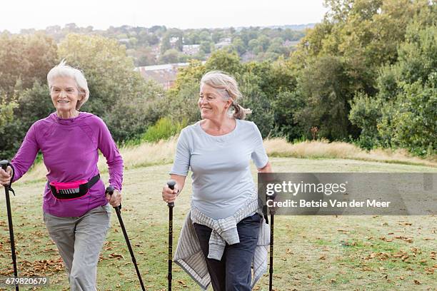 senior women walking with nordic walking poles. - walker stock-fotos und bilder