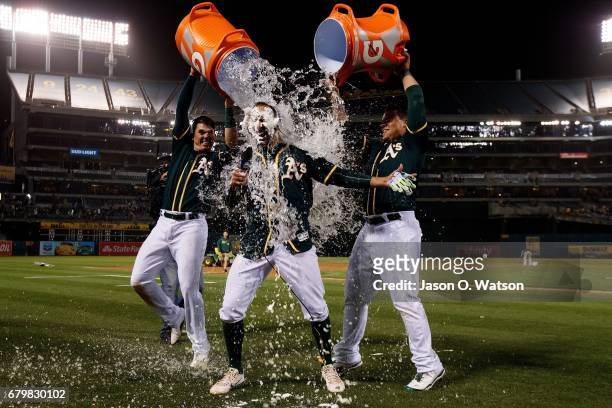 Ryon Healy of the Oakland Athletics and Bruce Maxwell pour water on Adam Rosales after hit he a two-run walk off single against the Detroit Tigers...