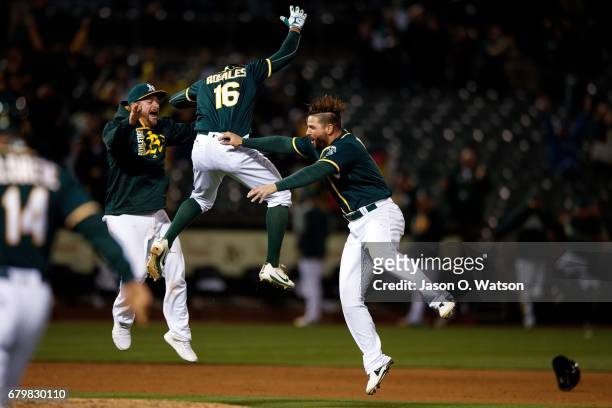 Adam Rosales of the Oakland Athletics celebrates with Yonder Alonso and Stephen Vogt after hitting a two-run walk off single against the Detroit...
