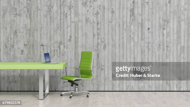 desk with laptop in front of concrete wall - berufliche beschäftigung stockfoto's en -beelden