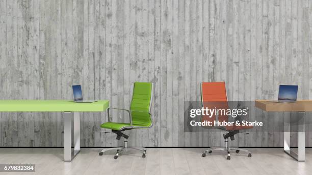 two desks with laptops in front of concrete wall - konzepte foto e immagini stock