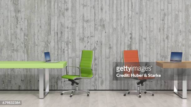 two desks with laptops in front of concrete wall - berufliche beschäftigung stock pictures, royalty-free photos & images