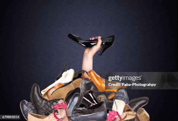 a woman is holding a shoe - shopaholic stockfoto's en -beelden