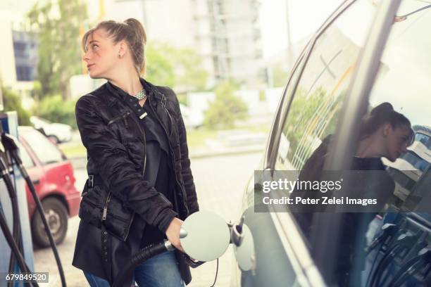 young woman refueling her car - refueling stock-fotos und bilder