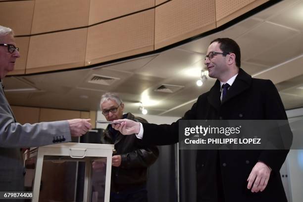 Former French Socialist party candidate Benoit Hamon hands over his ID at a polling station in Trappes, Paris' suburb, on May 7 during the second...