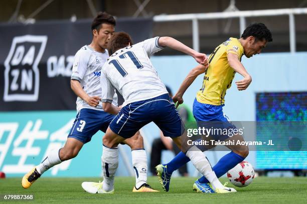 Taku Ushinohama of Tochigi SC competes for the ball against Kenta Fukumori and Koken Kato of Giravanz Kitakyushu during the J.League J3 match between...