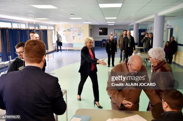 French presidential election candidate for the far-right Front National party Marine Le Pen walks to shakes hands with a woman as she votes at a...
