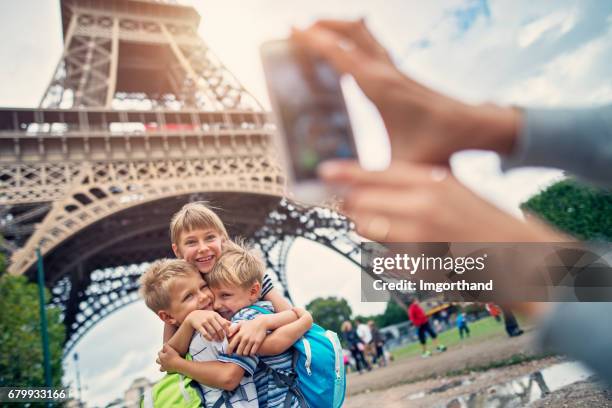 kid tourists embracing in front of the eiffel tower in paris, france - city break stock pictures, royalty-free photos & images