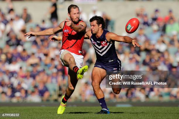 James Kelly of the Bombers kicks the ball under pressure from Brady Grey of the Dockers during the round seven AFL match between the Fremantle...