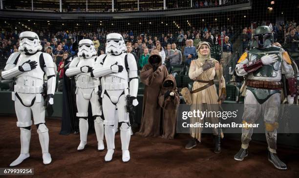 Star Wars characters including stormtroopers, jawas, Rey and Boba Fett stand during the singin of the Star Spangled Banner before game between the...