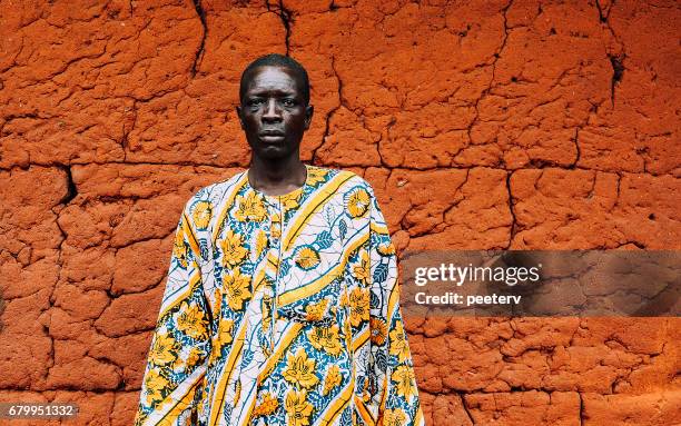 west african senior in front of mud hut. - mud face man stock pictures, royalty-free photos & images