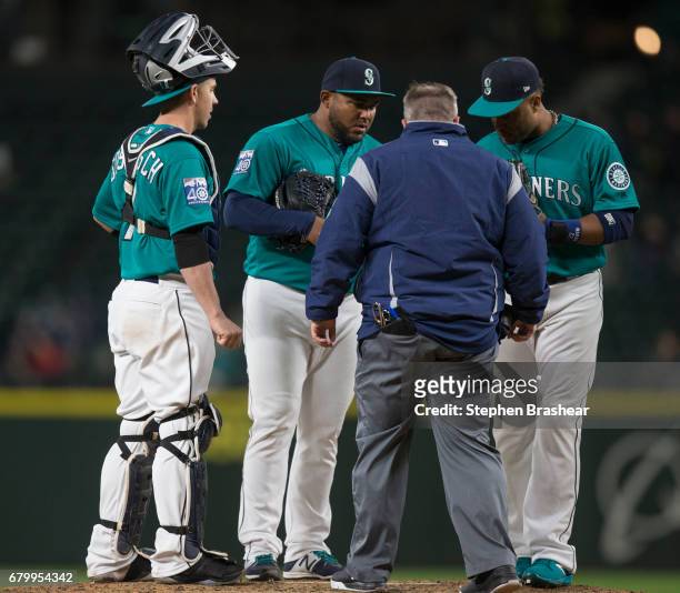 Relief pitcher Jean Machi, second from left, of the Seattle Mariners is checked out by a trainer as catcher Tuffy Gosewisch, left, of the Seattle...