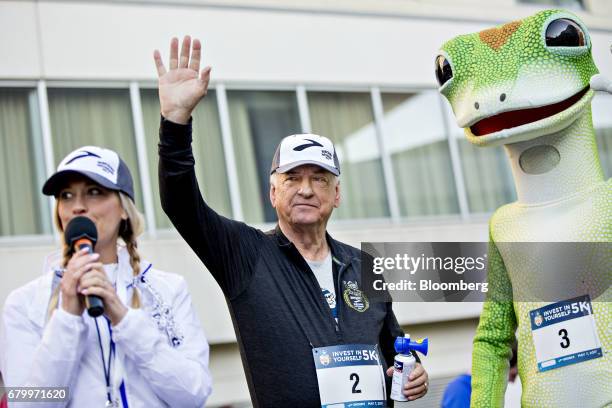 Tony Nicely, chief executive officer of the Government Employees Insurance Co. , waves to participants with the GEICO gecko mascot after signaling...