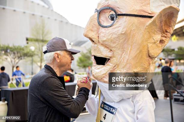 Tony Nicely, chief executive officer of the Government Employees Insurance Co. , shakes hands with a person wearing a costume in the likeness of...