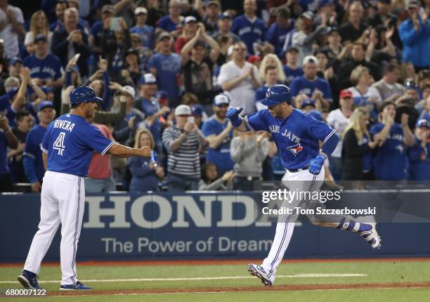 Justin Smoak of the Toronto Blue Jays is congratulated by third base coach Luis Rivera as he circles the bases after hitting a two-run home run in...