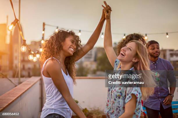 amigas bailando durante la fiesta en terraza - young adult fotografías e imágenes de stock