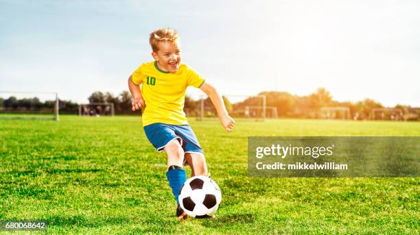 fröhlicher junge läuft auf fußball feld und tritte - 6 football player stock-fotos und bilder