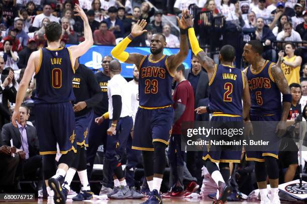 LeBron James, Kevin Love, and Kyrie Irving of the Cleveland Cavaliers high five each other during the game against the Toronto Raptors in Game Four...