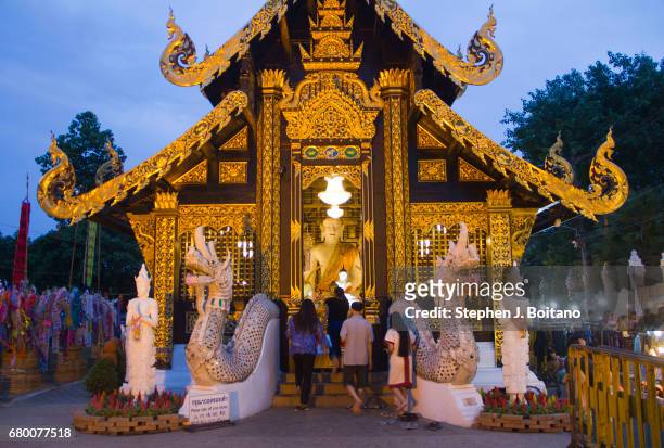 People walk into a temple near the Sunday Night Market by Rachadamnoen Rd in Chiang Mai, Thailand.