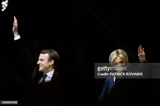 French president-elect Emmanuel Macron waves to the crowd next to his wife Brigitte Trogneux in front of the Pyramid at the Louvre Museum in Paris on...