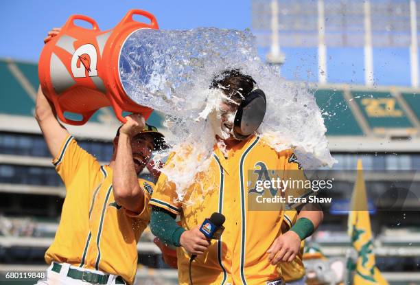 Ryon Healy of the Oakland Athletics is covered in water by Adam Rosales after he hit a walk-off home run in the ninth inning against the Detroit...