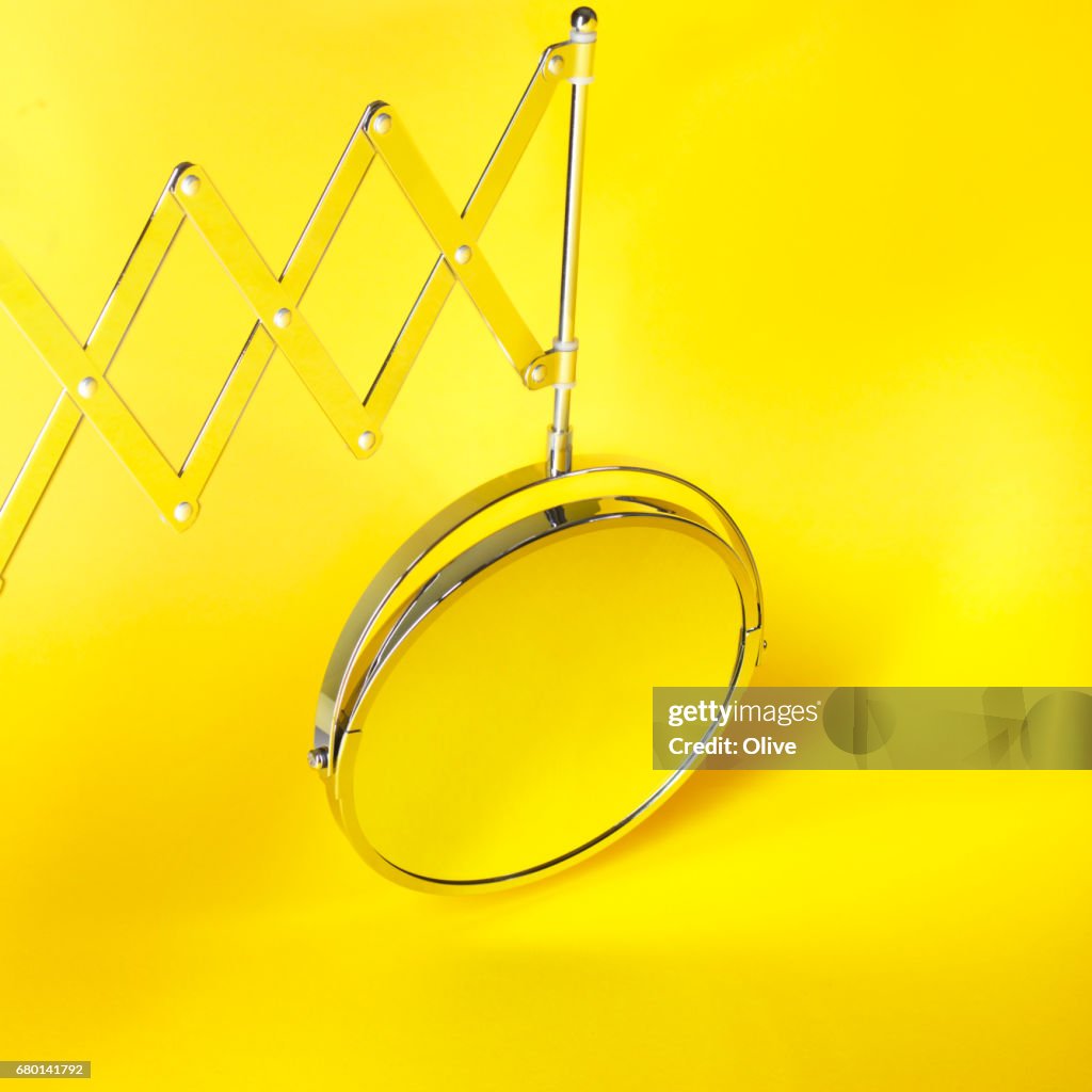 Magnifying mirror on yellow background