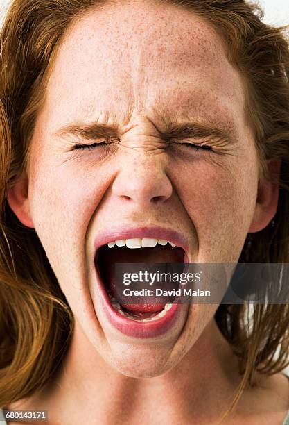 freckled young woman screaming. - gritar fotografías e imágenes de stock