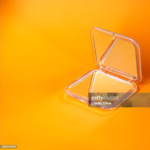pocket mirror on orange background - fond coloré stock pictures, royalty-free photos & images