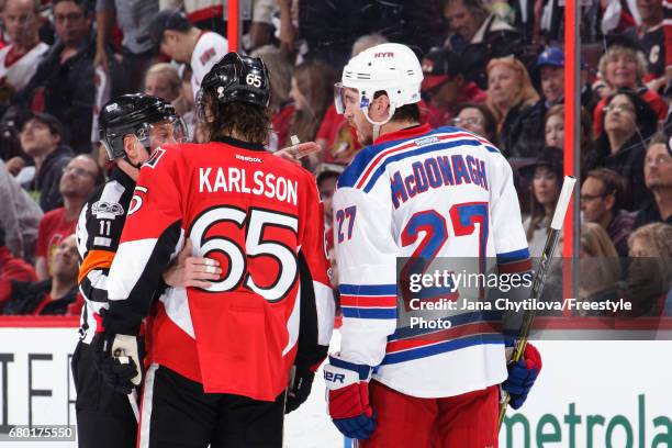 Referee Kelly Sutherland talks to Erik Karlsson of the Ottawa Senators and Ryan McDonagh of the New York Rangers following penalties being called in...