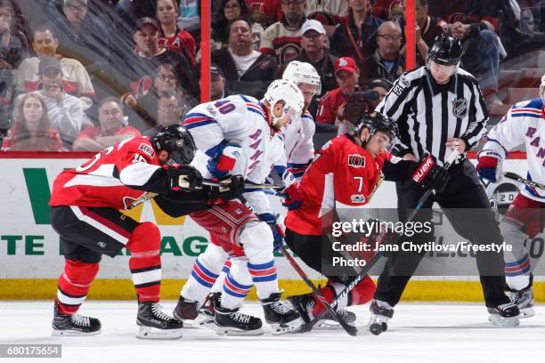 Linesman Pierre Racicot looks on as Kyle Turris and Clarke MacArthur of the Ottawa Senators battles for the puck against Michael Grabner and Kevin...