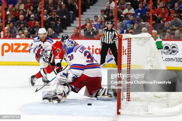 Kyle Turris of the Ottawa Senators scores the overtime winner against Henrik Lundqvist of the New York Rangers as Oscar Lindberg of the New York...