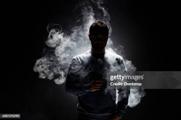 黒の背景に男と煙の断片 - electronic cigarette smoke ストックフォトと画像