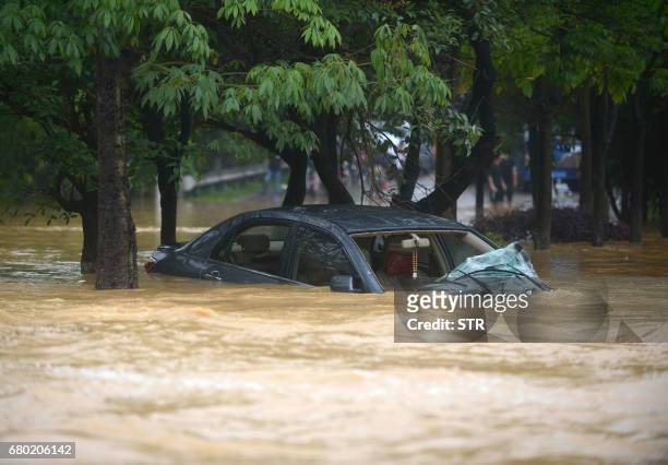 This photo taken on May 7, 2017 shows a car swept away by floodwaters in Guangzhou's Zengcheng District, southern China's Guangdong province. Parts...