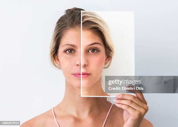 middle age woman holding photo of face when she was younger - faltenreduktion stock-fotos und bilder